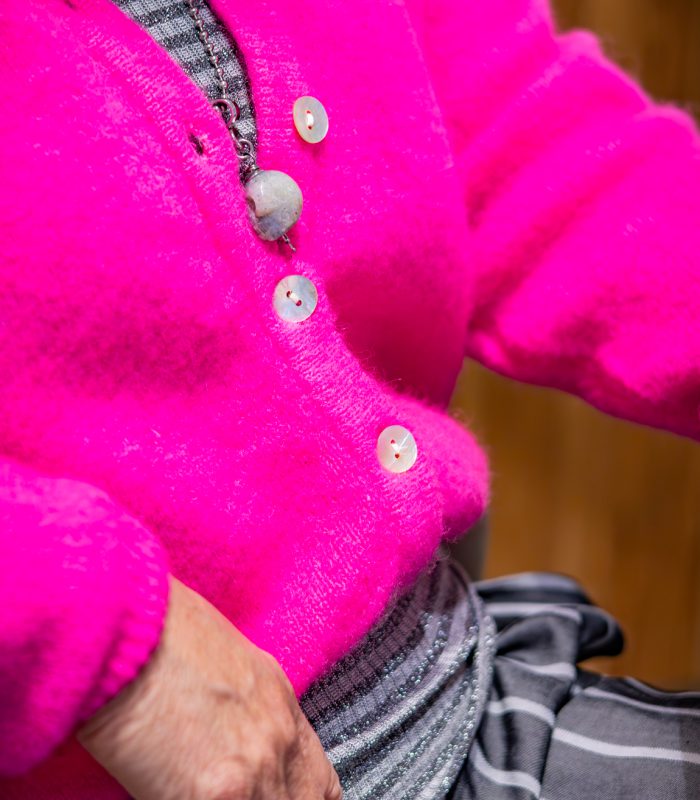 Detail van felroze kledingstuk met aandacht voor kleur en textuur